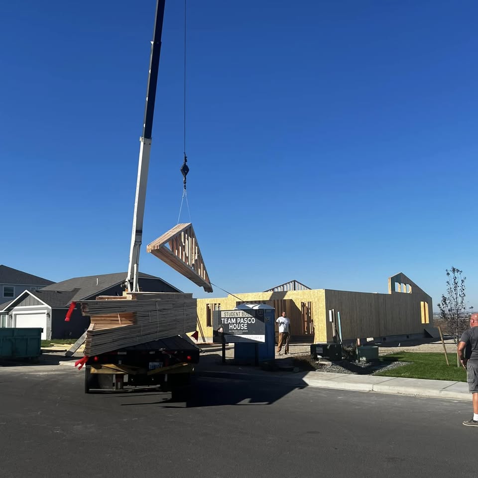A crane lifting a load off a delivery truck at a jobsite